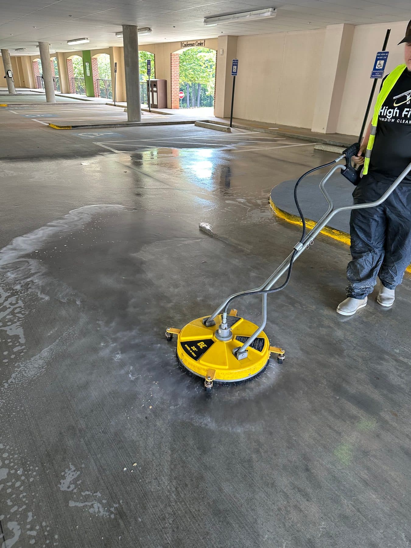 A High Five cleaner using a yellow surface cleaner on a parking deck